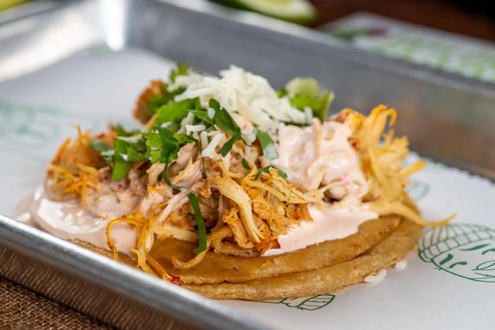 Taylor's Tacos Chicago juicy shredded chicken taco topped with crispy onions, signature creamy sauce, cilantro and cotija cheese